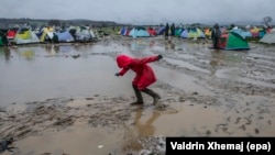 Një vajzë refugjate ecë nëpër baltë në një kamp refugjatësh